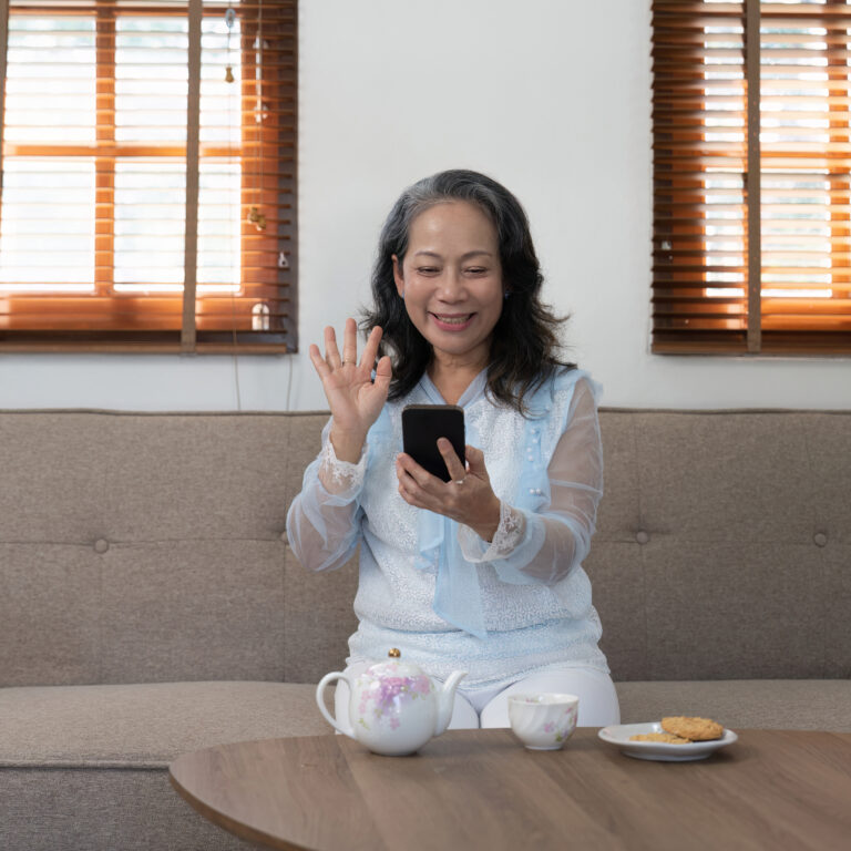 Asian old woman talking on the phone in the living room at an Elder Care Home in Oakland Ca